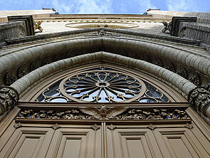 Das sandfarbene Eingangsportal der Neustrelitzer Schlosskirche. Das Foto wurde von unten nach oben aufgenommen und legt den Fokus auf die Verzierungen.