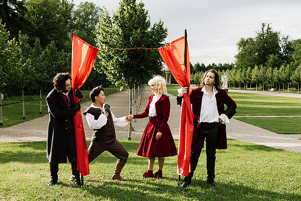 Vier verkleidete Schauspieler spielen im Schlosspark.