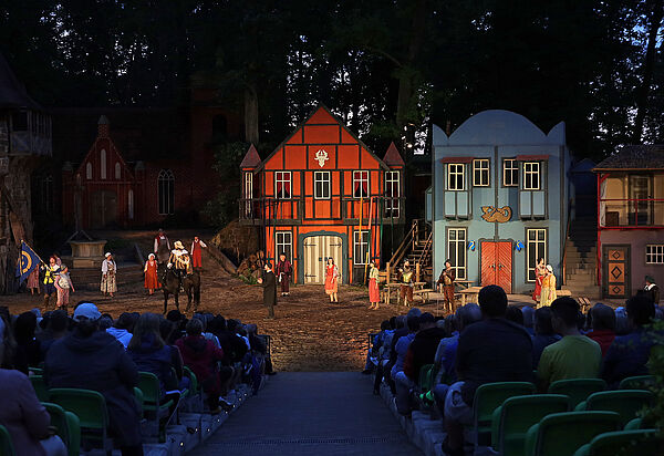 Das Bühnenbild der Müritz-Saga. Im Vordergrund sitzt Publikum. Die Naturbühne ist erleuchtet.