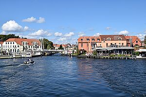 Malchow Im Vordergrund: die Müritz. Dahinter schieben sich Häuser der Malchower Innenstadt ins Bild. Eine Brücke verbindet an einem Kanal beide Uferseiten.