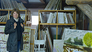 Eine Frau sieht sich einem Raum voller Leinwände um.