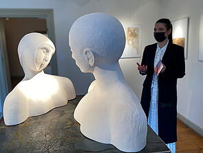 Annekathrin Siems steht neben zwei Büsten und spricht.