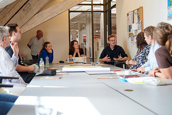 Menschen an einem großen Tisch. Sie sprechen.