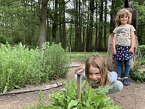 Zwei Mädchen schauen sich den Kräutergarten an.
