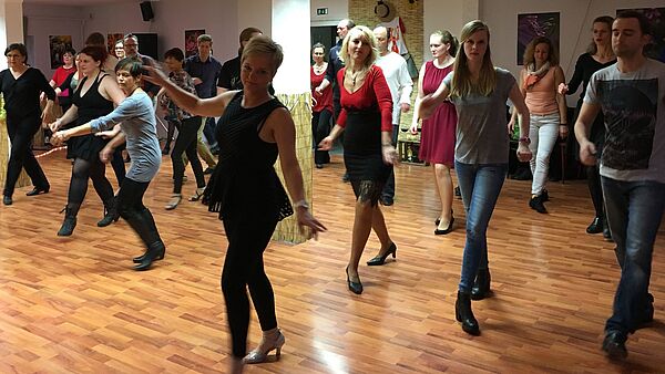 Ein Saal, in dem Frauen und Männer tanzen.