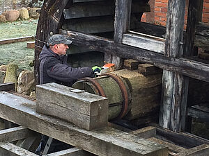Ein Arbeiter arbeitet an der Halterung des Wasserrads.