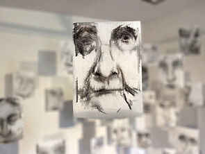 Detailaufnahme eines weißen Stoffs. Darauf befindet sich ein gezeichnetes Gesicht.