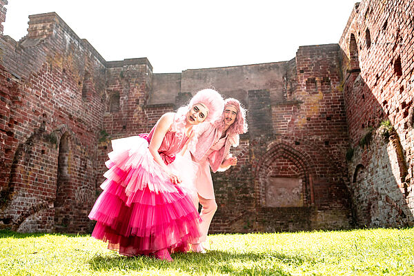 Zwei geschminkte und verkleidete Schauspieler stehen vor der Ruine eines Klosters.