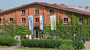 Die Scheune Bollewick, ein zweistöckiges Gebäude mit einem flachen Spitzdach. An der Fassade wächst Efeu.