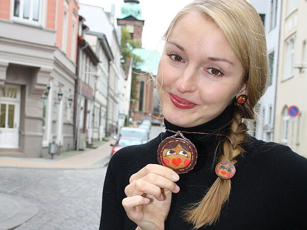 Nadja Bossert hält den bunten Anhänger ihrer Kette in der Hand.