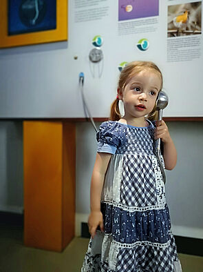 Ein Mädchen hält einen Hörer an ihr Ohr.