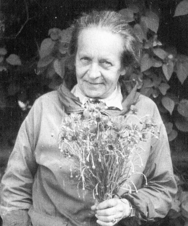 Käthe Miethe Ein Schwarz-Weiß-Foto von Käthe Miethe mit einem Blumenstrauß in der Hand.