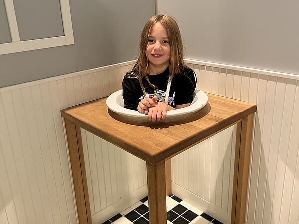 Hanna schaut von einem Teller in einen Raum. Eine optische Täuschung.