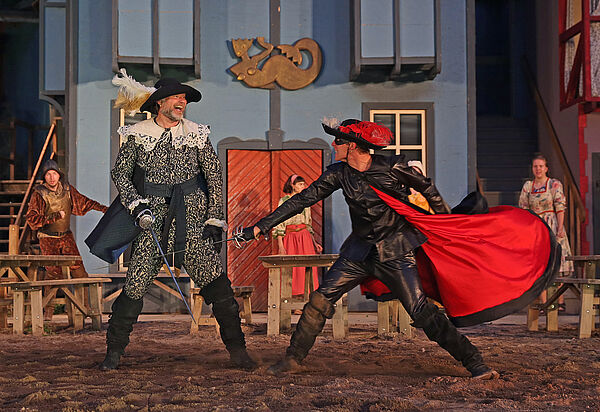 Zwei Männer kämpfen mit Degen. Sie tragen historische Kostüme.