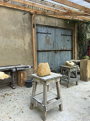 Auf Hockern liegen Skulpturen.