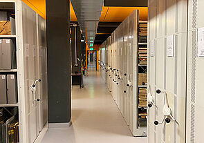 Der Raum ragt schätzungsweise mehr als 50 Meter in die Tiefe. Links und rechts stehen unzählige Rollregale. Manche sind geschlossen, andere geöffnet.