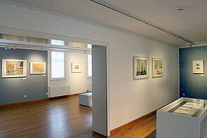 Sechs beleuchtete Bilder hängen an den Wänden.