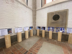 Neun Holzstelen. Darauf befinden sich Informationstafeln zum Dom und zu den geplanten Uecker-Fenstern.