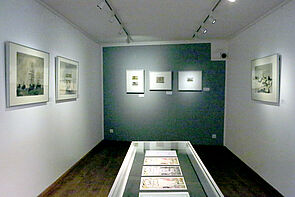 Blick durch einen Ausstellungsraum. Die Bilder sind angestrahlt.