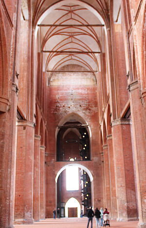 st_georgen_kirche_wismar_hauptschiff Das Hauptschiff ist ein leerer Raum. Einige Besucherinnen und Besucher gehen ihn entlang.